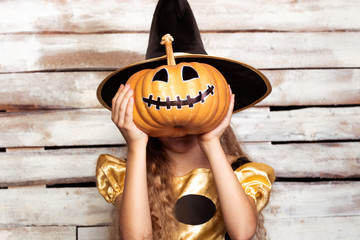 Little with covering face with painted pumpkin