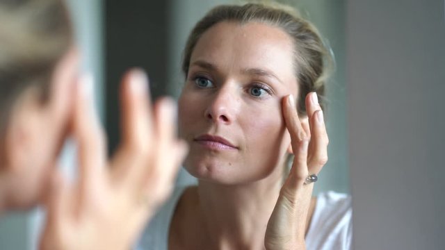 Portrait of woman looking at her face in mirror