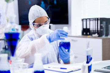 Researcher analyzes a tube with a blue liquid from which smoke comes out