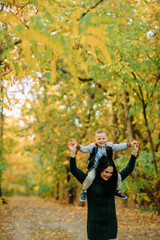 A mother and son play, have a fun and laugh in autumn forest.