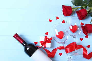 Fototapeta na wymiar Wine and glasses and hearts on a colored background top view. Background to the day of St. Valentine.