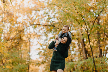 A mother and son play, have a fun and laugh in autumn forest.