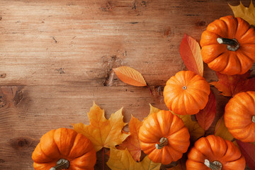 Autumn Thanksgiving background. Pumpkins and maple leaves on wooden table top view.
