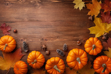 Autumn Thanksgiving background. Pumpkins, acorns and leaves on rustic wooden table top view.