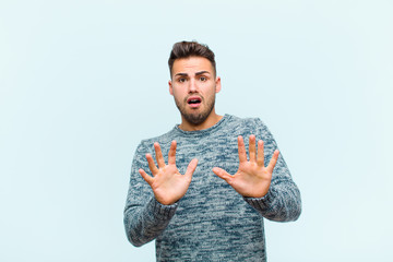young hispanic man feeling terrified, backing off and screaming in horror and panic, reacting to a...
