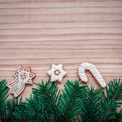 Frame with fir branches and Gingerbread cookies on a wooden brown background. Top view.