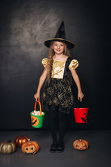 Little witch with colorful pumpkin buckets