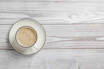 Cup of coffee with foam over white wooden table