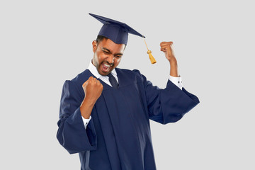 education, graduation and people concept - happy smiling indian male graduate student in mortar...