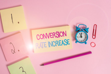 Writing note showing Conversion Rate Increase. Business concept for Ratio of Total Visitors who perform desired actions Blank notepads marker rubber band alarm clock clip colored background
