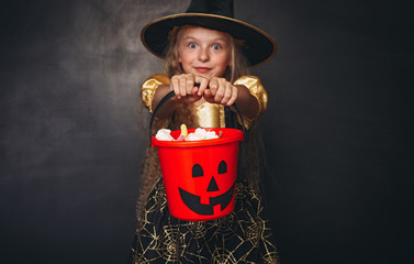 Amazed little witch with red pumpkin bucket