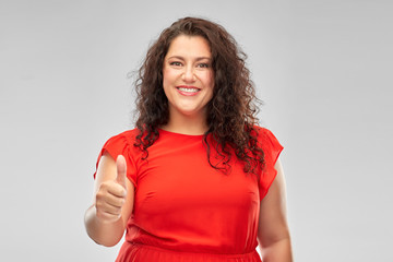 people and gesture concept - happy woman in red dress showing thumbs up over grey background