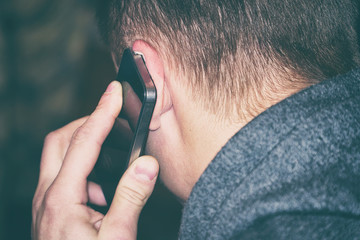 A man talking on the phone. The phone is at the man's ear. Rear view