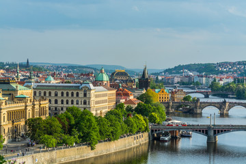 Aerial view of citycape of old town of Prague, with a lot of  rooftops, churches, and the landmark of Charles Bridge, and Vltava river.