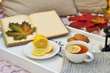 old book with autumn leaves and hot tea