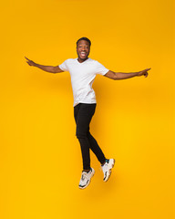 Fototapeta na wymiar African American Guy Jumping Having Fun Over Yellow Background