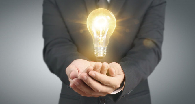 Hand of holding illuminated light bulb, innovation inspiration concept