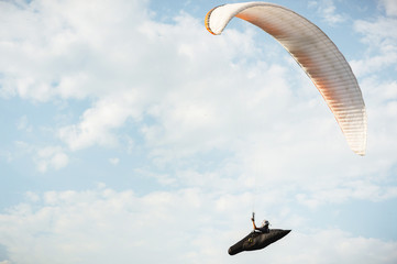 A paraglider flies in the sky in a cocoon suit on a paraglider against the sky and clouds....