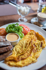 Fresh omelette served with green salad, tomatoes. sause and breab - close up view. Cup of coffee on a background. Traditional breakfast. Healthy food.