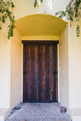 Fototapeta na wymiar A rustic wooden door set deep in a stucco covered adobe wall plastered in a cream color