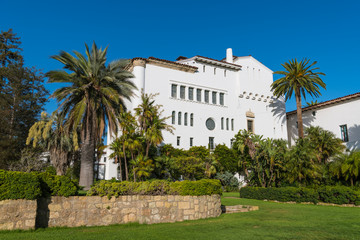 Fototapeta na wymiar Historic white Spanish colonial revival architecture building in beautiful tropical gardens under a perfect blue sky