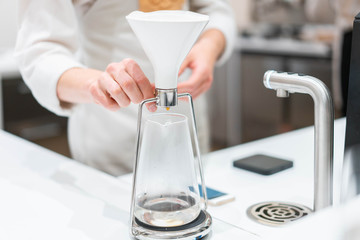 process of preparation black coffee in chemex pour over coffee maker in bright modern cafe. Alternative ways of brewing coffee.