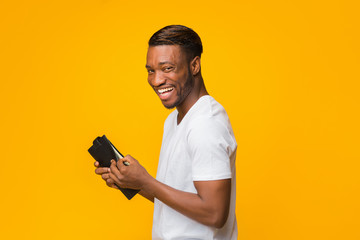 Happy African American Guy Holding Money Standing Over Yellow Background