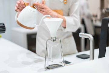 process of preparation black coffee in chemex pour over coffee maker in bright modern cafe....