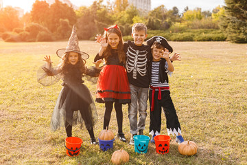 Scary cute children in Halloween costumes standing in field