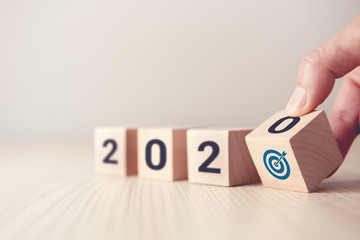Hand flip over wood wooden cubes with New year 2020 and goal icon concept.