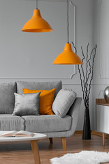 Orange lamp above grey scandinavian sofa in modern interior © Photographee.eu