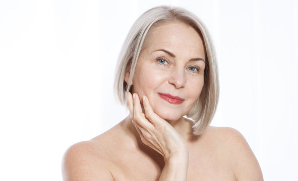 Portrait of cheerful senior woman smiling while looking away at spa. Happy mature woman after spa massage and anti-aging treatment on face. Realistic images with their own imperfections.