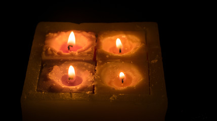 Four burning candles on a dark background.