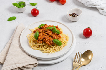 Italian cuisine, food. Spaghetti bolognese with basil garnish on white plate on white background....
