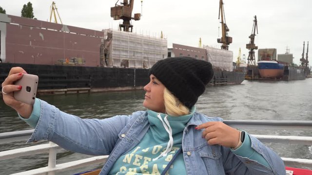 Gdansk, Poland - September 2019: A girl in a hat on the deck of a ship takes a selfie using a smartphone.