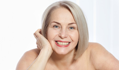Fifty year old woman is very pleased with her well-groomed face. Plastic surgery collagen injections. Macro face. Selective focus on face. Realistic images with their own imperfections.