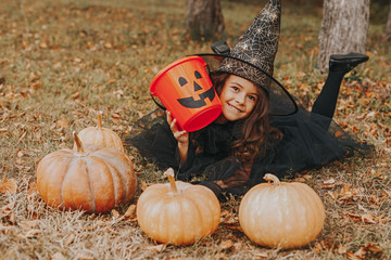 Cute girl with pumpkins and empty candy collector