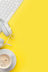 Office yellow workplace with coffee cup, headphones and pc