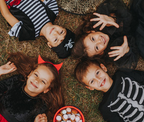 Cheerful friends lying on lawn on Halloween Day