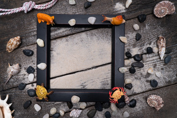 Summer time concept with sea shells on wooden background and sand.