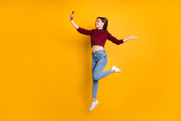 Fototapeta na wymiar Full length profile side photo of cheerful cute girl offer holiday making photos wearing maroon sweater isolated over yellow background
