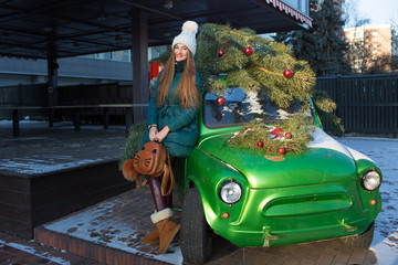 Beautiful woman with New Year decorations and balls on background of green retro car.Christmas and New Year holidays.