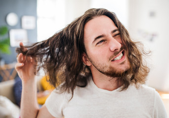 A portrait of young man with long hair indoors, a close-up.