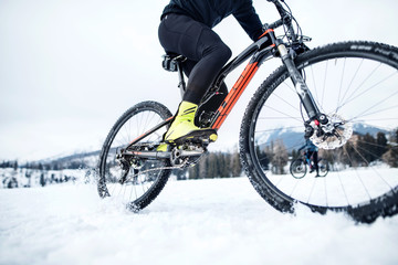 Midsection of mountain biker riding in snow outdoors in winter.