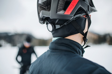 A rear view of mountain biker standing outdoors in winter, close-up.