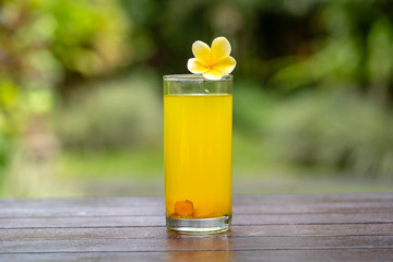 Energy tonic drink with turmeric, ginger, lemon and honey in glass, nature background, close up