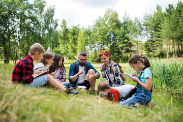 Group of school children with teacher on field trip in nature, learning science.