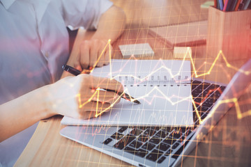 Financial charts displayed on woman's hand taking notes background. Concept of research. Double exposure