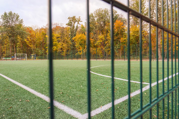 View on mini-football court with artificial grass through green fence