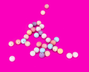 Set of multi-colored beads on a pink background.Top view.